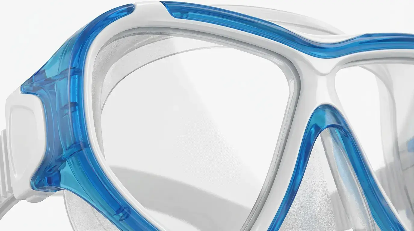 Close-up of a polycarbonate diving mask showing injection-molded frame and anti-fog lens coating